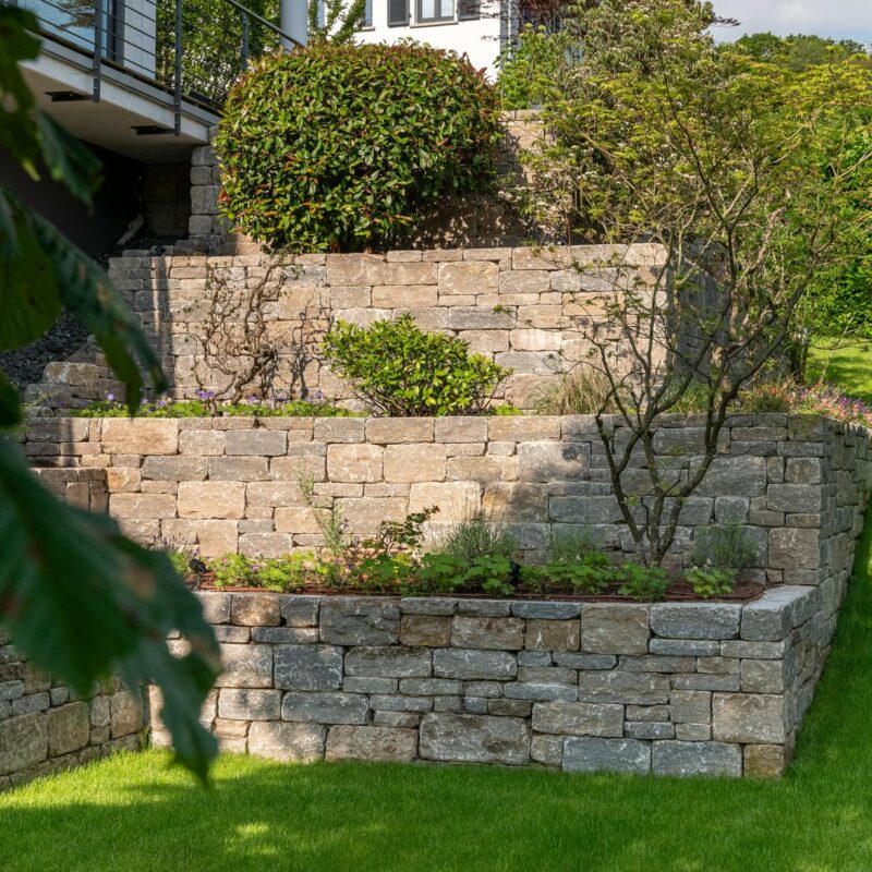 Terrassierter Hanggarten mit mehreren Trockenmauern und Bepflanzung