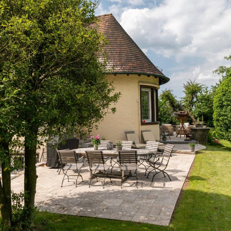 Natursteinterrasse mit Sitzgruppe an einem Altbau mit Turmdach