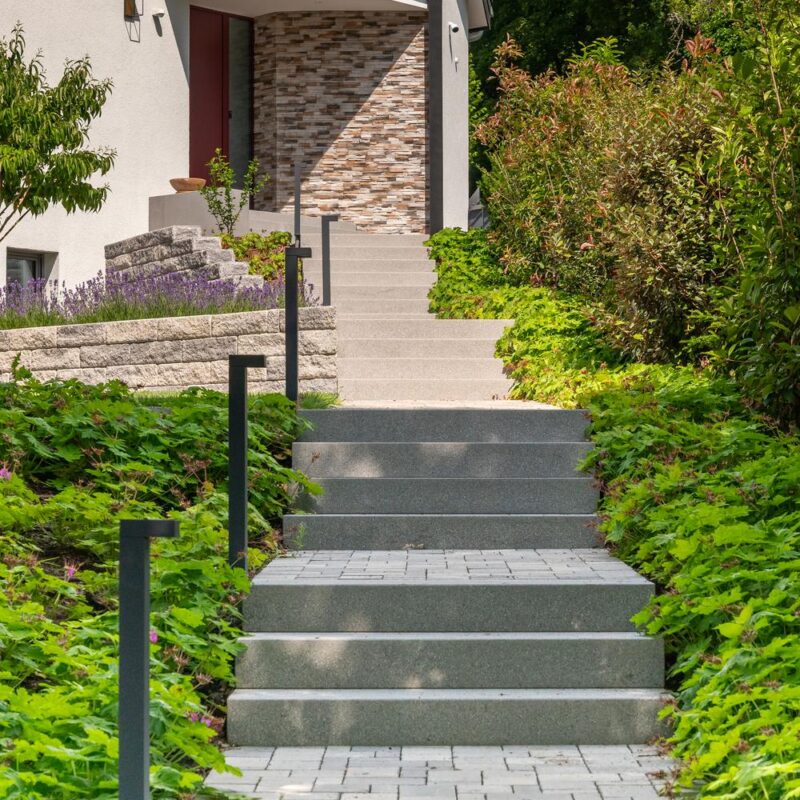 Treppenanlage mit Pollerleuchten und Bodendeckern zum Hauseingang