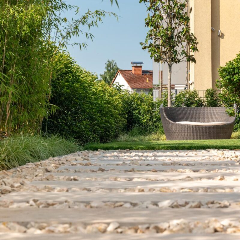 Weg aus Trittplatten im Kies zwischen Bambus und Sitzplatz