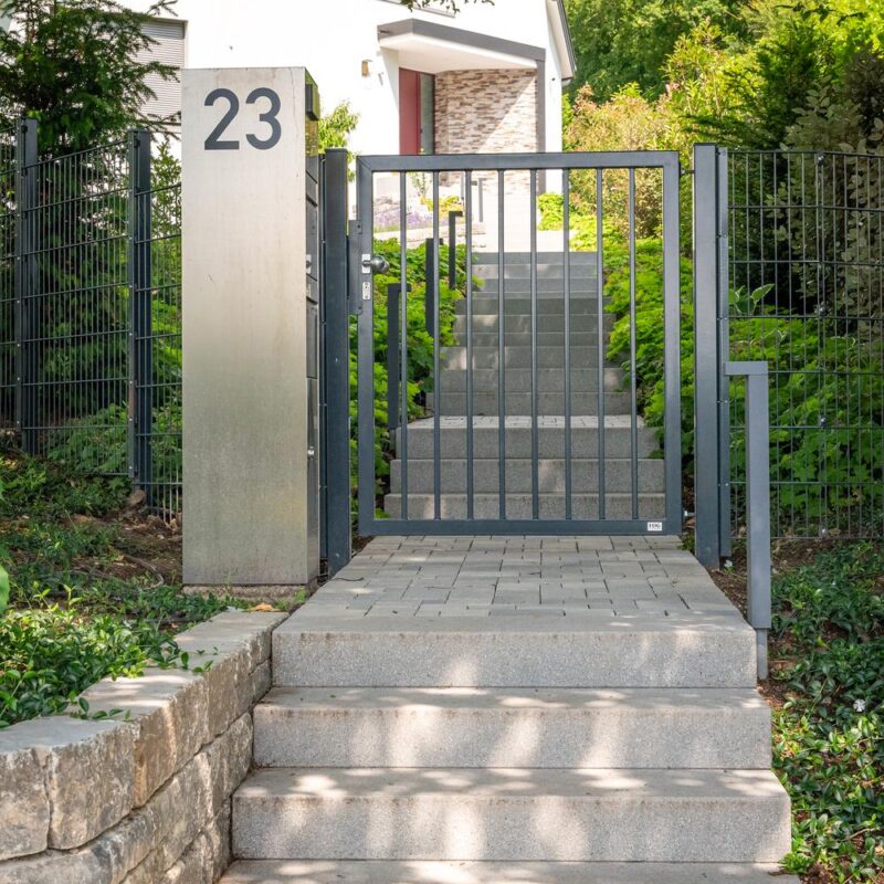 Grundstückszugang mit Gartentor, Blocktreppe und Natursteinmauer